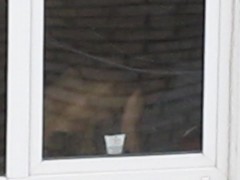 Sexy redhead stands by her window with her tits out in the 