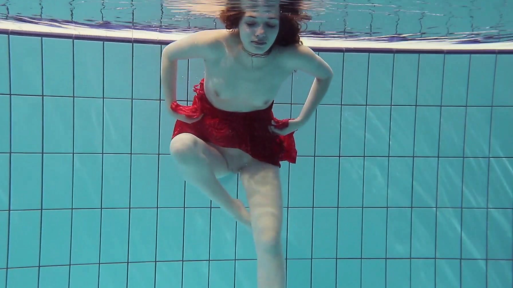 Red Dressed teen swimming with her eyes opened